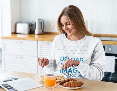 Mockup of a Happy Woman with a Sweatshirt Having Breakfast at Home 