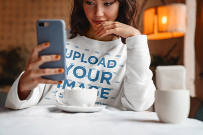 Sweatshirt Mockup of a Woman Taking a Selfie in a Coffee Shop
