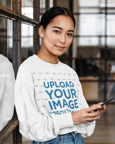 Mockup of a Woman with a Cropped Sweatshirt Holding a Phone
