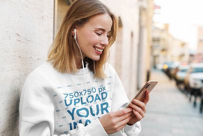 Sweatshirt Mockup of a Happy Woman Listening to Music on the Street