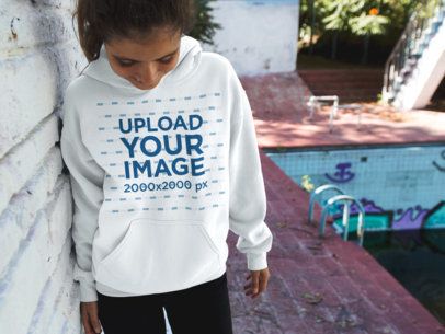 Young Woman Looking at her Feet While Wearing a Pullover Hoodie Near an Abadoned Pool Mockup