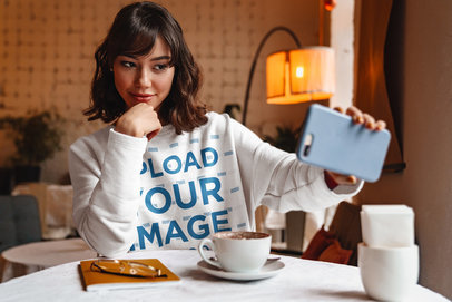 Sweatshirt Mockup of a Woman Taking a Selfie at a Coffee Shop