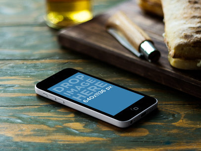 Mockup of a Portrait Positioned iPhone 5C Featuring a Wooden Bistro Table