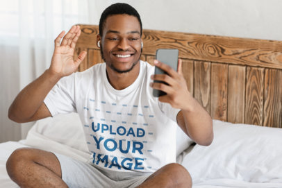 T-Shirt Mockup of a Man Doing a Video Call in His Bedroom