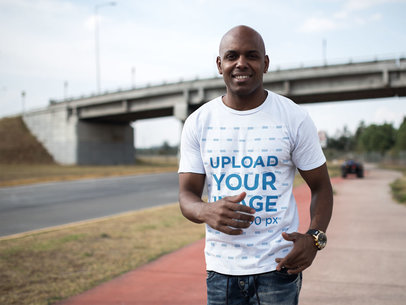 Bald Man Smiling While Wearing a Round Neck Tee in a Quiet Street