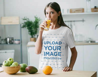 T-Shirt Mockup of a Woman Drinking Orange Juice in the Kitchen