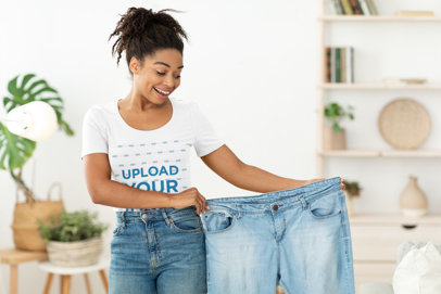 T-Shirt Mockup of a Woman Holding a Pair of Old Jeans