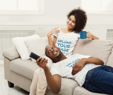 T-Shirt Mockup of a Happy Couple Watching TV in Their Living Room