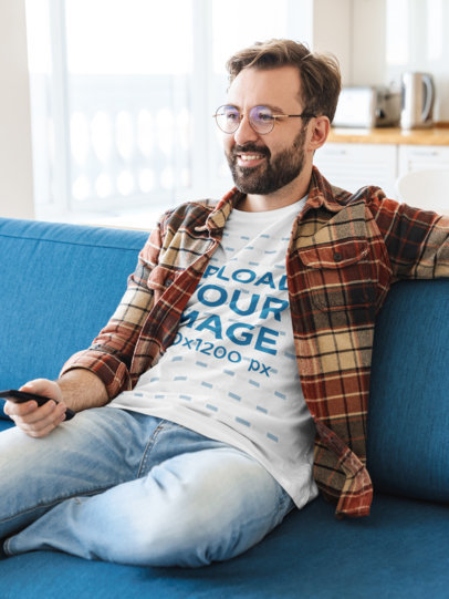 T-Shirt Mockup of a Bearded Man Watching TV at Home