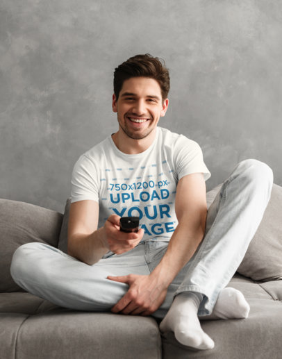 T-Shirt Mockup of a Young Man Watching TV at Home