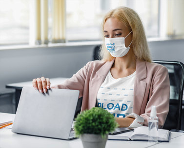 Face Mask Mockup Featuring a Woman Wearing a Customizable T-Shirt at an Office 
