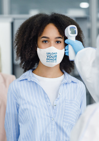 Face Mask Mockup Featuring a Curly-Haired Woman Getting Her Temperature Checked 