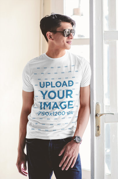 T-Shirt Mockup of a Man with Sunglasses Standing by a Window 