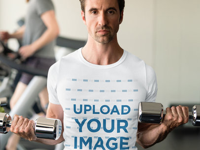 T-Shirt Mockup of a Muscled Man Using Dumbbells at the Gym