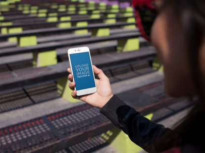 Over-the-Shoulder Mockup of a Woman on a Bench Holding an iPhone 6
