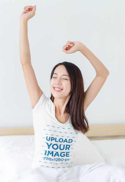 T-Shirt Mockup Featuring a Woman Stretching Her Arms on a Bed