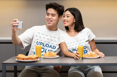 T-Shirt Mockup of a Happy Couple Taking a Selfie While Having Breakfast 