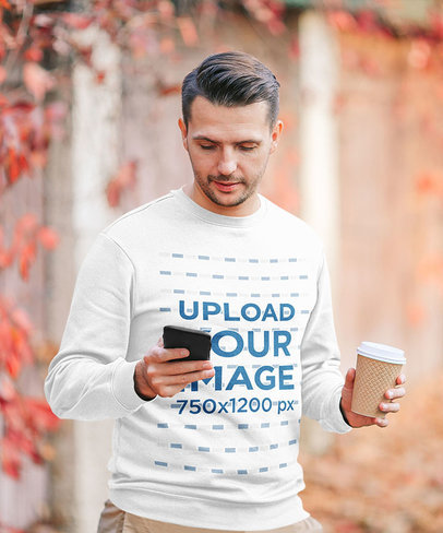 Sweatshirt Mockup Featuring a Man Checking His Phone on an Autumn Day