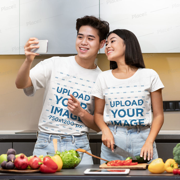 T-Shirt Mockup Featuring a Couple Taking a Selfie While Cooking