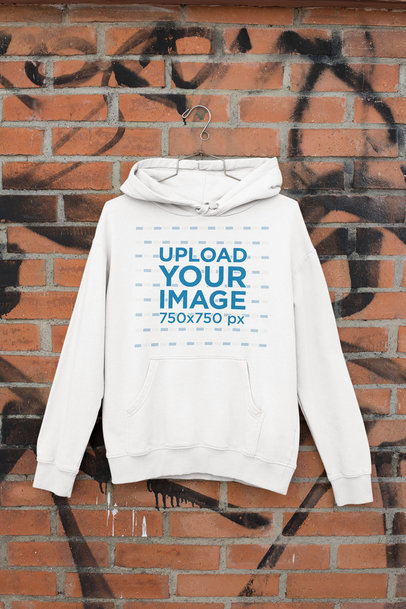Mockup of a Hanging Hoodie by a Brick Wall 
