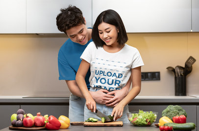 T-Shirt Mockup Featuring a Young Couple Cooking at Home