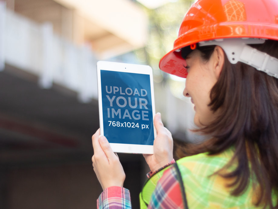 Mockup of a Woman Holding an iPad at a Construction Site