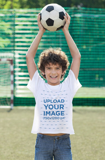 T-Shirt Mockup of a Happy Boy Holding a Soccer Ball Over His Head 