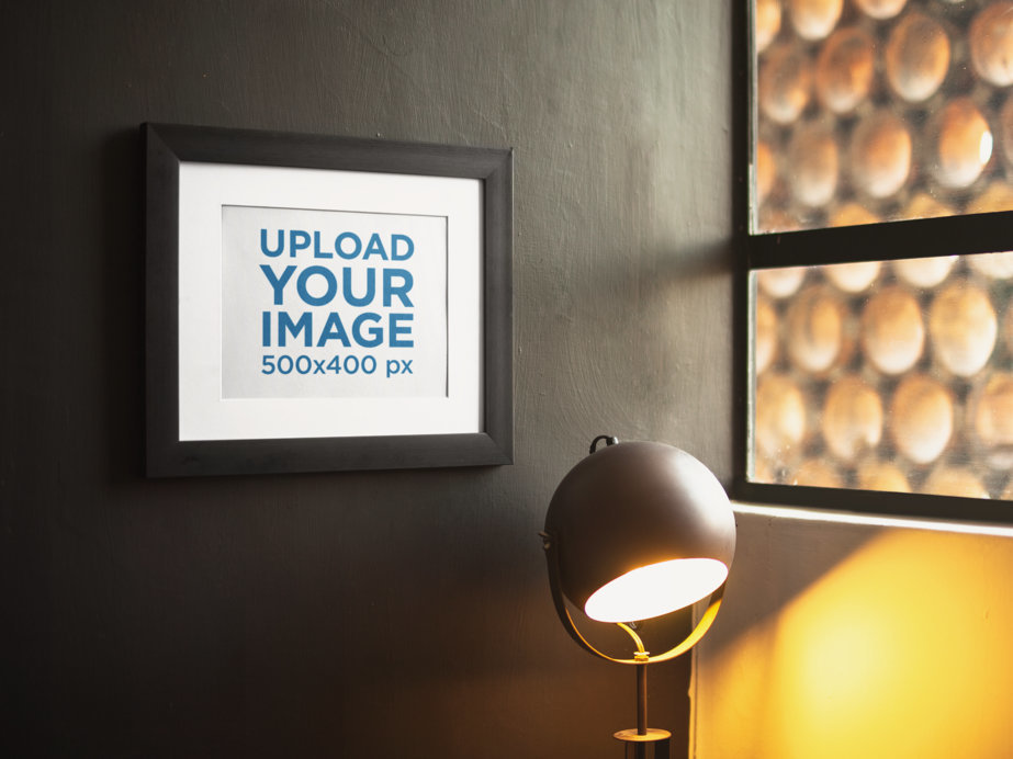 Framed Art Print Mockup on a Black Wall Near a Lamp