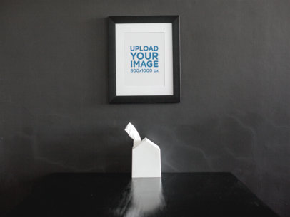 Framed Art Print Mockup On a Black Wall Over a Black Table