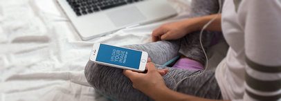 Girl Sitting on her Bed Listening to Music With Her iPhone 6 a14259wide