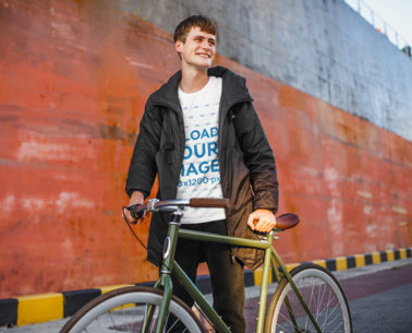 T-Shirt Mockup of a Happy Young Man Posing With a Bike 