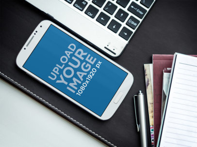 Mockup of a Samsung Galaxy 4 Next to a Pile of Notebooks