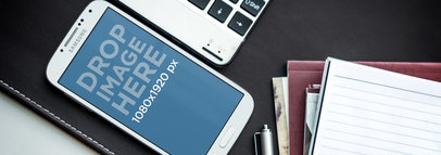 Mockup of a Samsung Galaxy 4 over a Leather Surface by some Notebooks