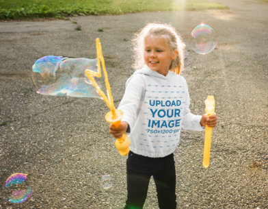 Hoodie Mockup of a Girl Playing With Bubbles at a Park