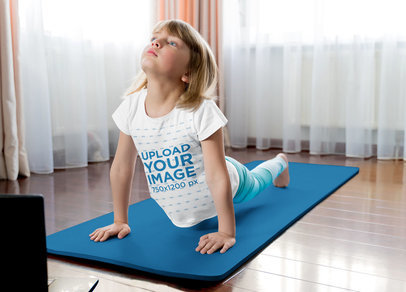 T-Shirt Mockup of a Little Blonde Girl Doing Yoga in Her House