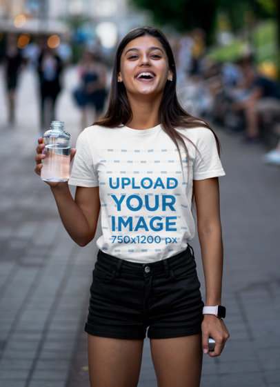 Tee Mockup of a Joyful Woman Holding a Glass of Water