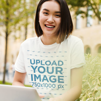 T-Shirt Mockup of a Smiling Woman with Short Hair Using Her Computer
