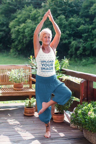 Tank Top Mockup of a Senior Yogi Practicing Outside of Her Cabin in the Woods
