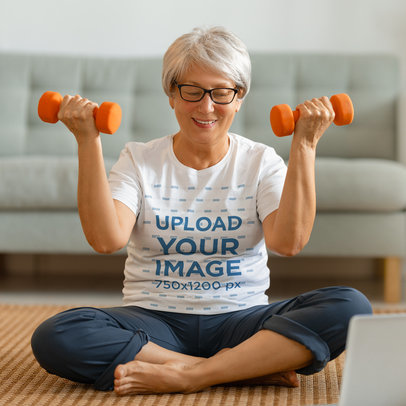 T-Shirt Mockup Featuring a Senior Woman Holding a Pair of Dumbbells 