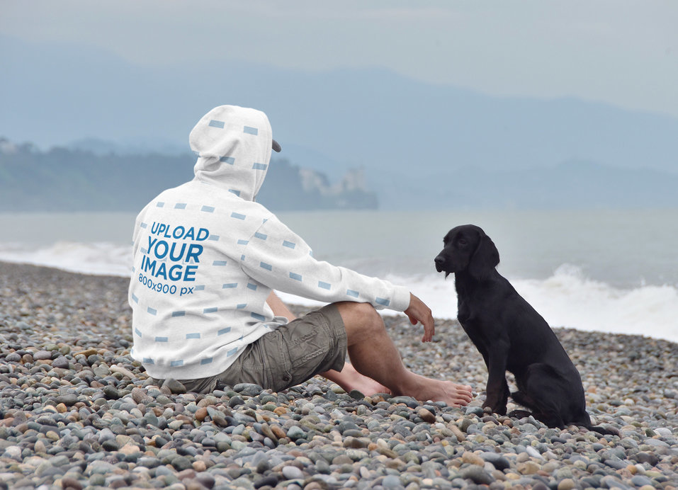 Hoodie Mockup of a Man Sitting at a Beach with His Dog