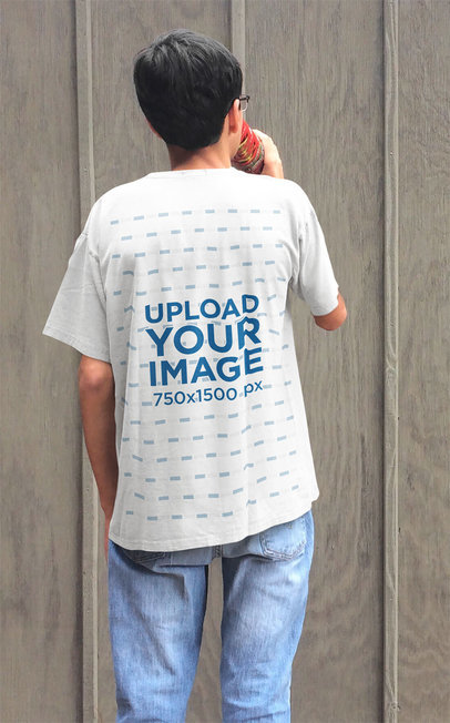 T-Shirt Mockup of a Young Man Staring at a Wooden Wall
