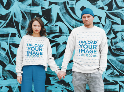 Sweatshirt Mockup Featuring a Serious Couple Posing by a Graffiti Wall 