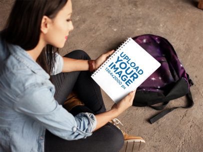 Young Woman Looking at a School's Notebook Template Near Her Backpack