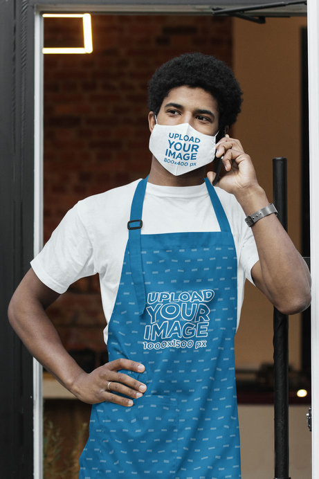 Face Mask and Apron Mockup of a Young Barista Talking on the Phone