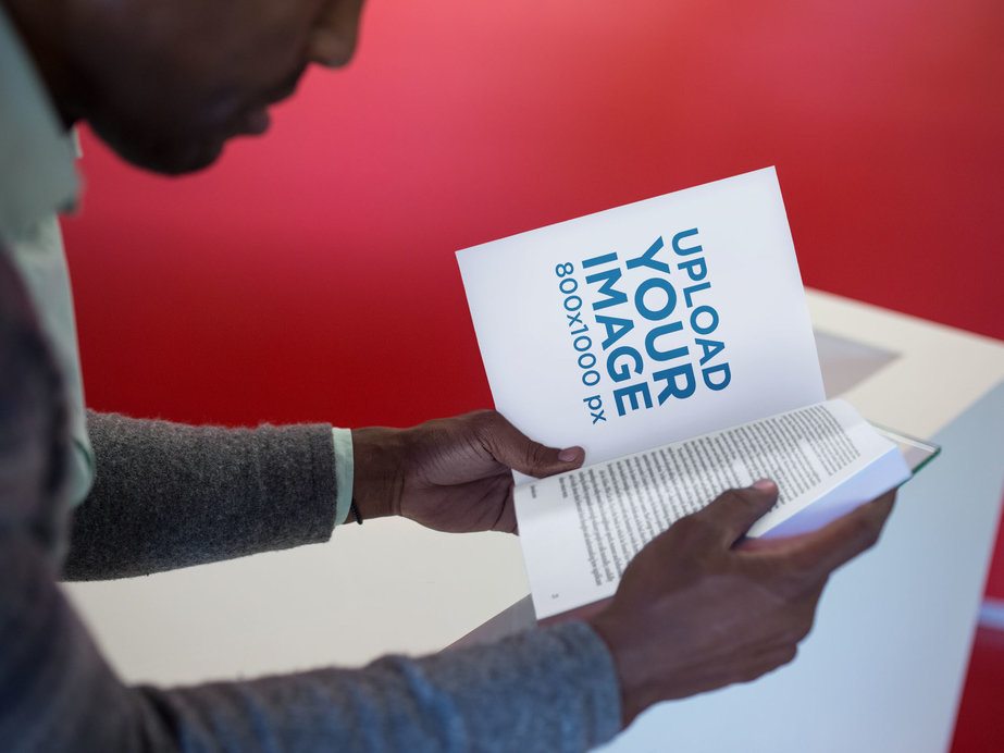 Man Reading a Book Mockup While Sitting Down in a Red Room