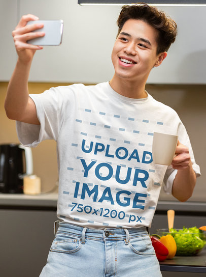 T-Shirt Mockup of a Young Man Taking a Selfie in a Kitchen