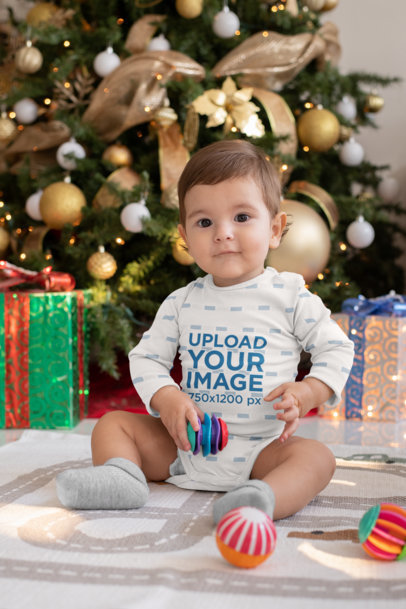 Sublimated Onesie Mockup Featuring a Baby by a Christmas Tree 