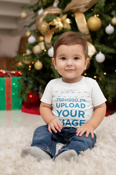 T-Shirt Mockup Featuring a Baby Boy Sitting by a Christmas Tree