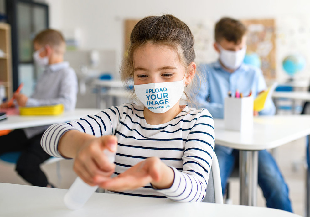 Face Mask Mockup of a Little Girl in a Classroom Using Antibacterial Gel