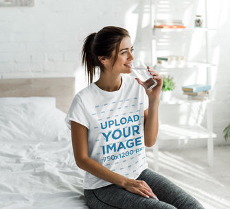 T-Shirt Mockup Featuring a Woman at Home Drinking Water 